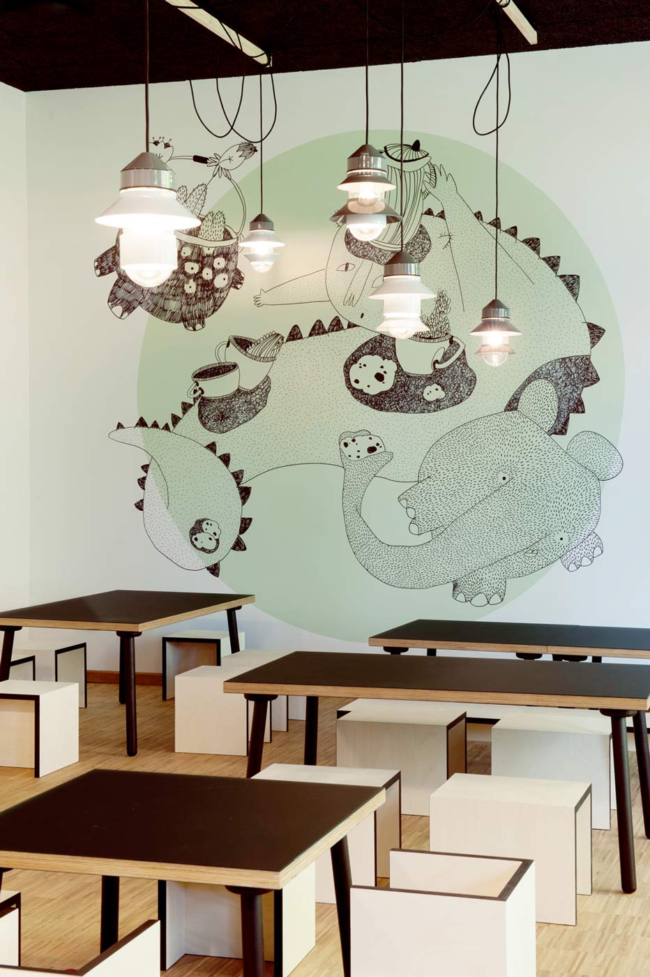 Ausdrucksstarke Pendelleuchten und Wandgrafik im Kindercafé